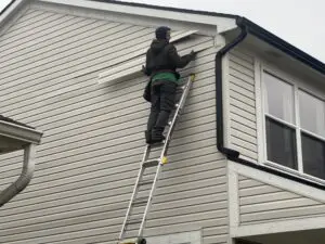 A man standing on the ladder and fixing the vinyl sliding